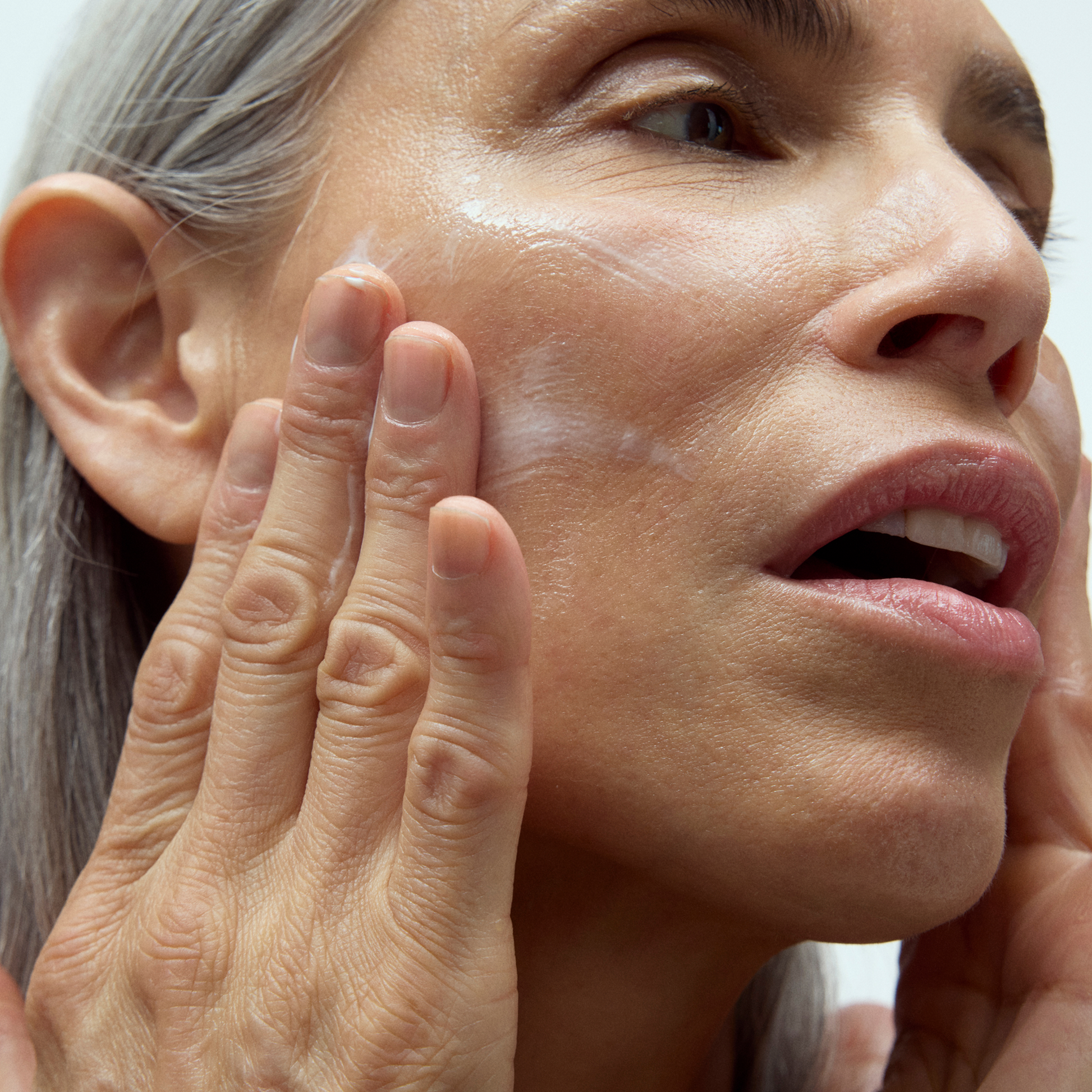 Image of model swiping Dieux's Instant Angel Lipid-Rich Firming Moisturizer onto face