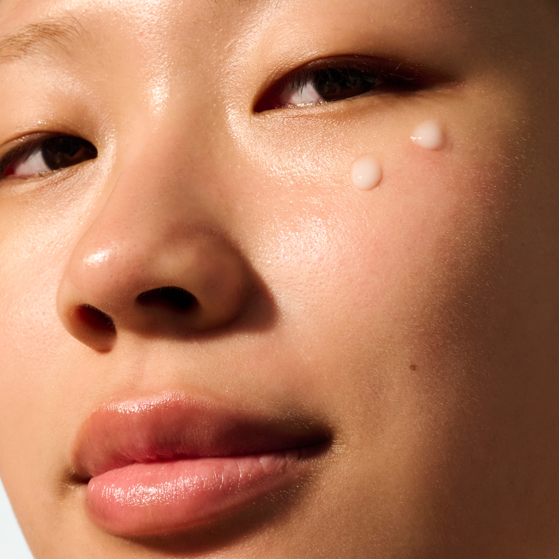 Model with two drops of Auracle Eye Serum applied on the eye area