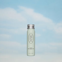Dieux Auracle Eye Serum Refill on a blue and white cloud background. 