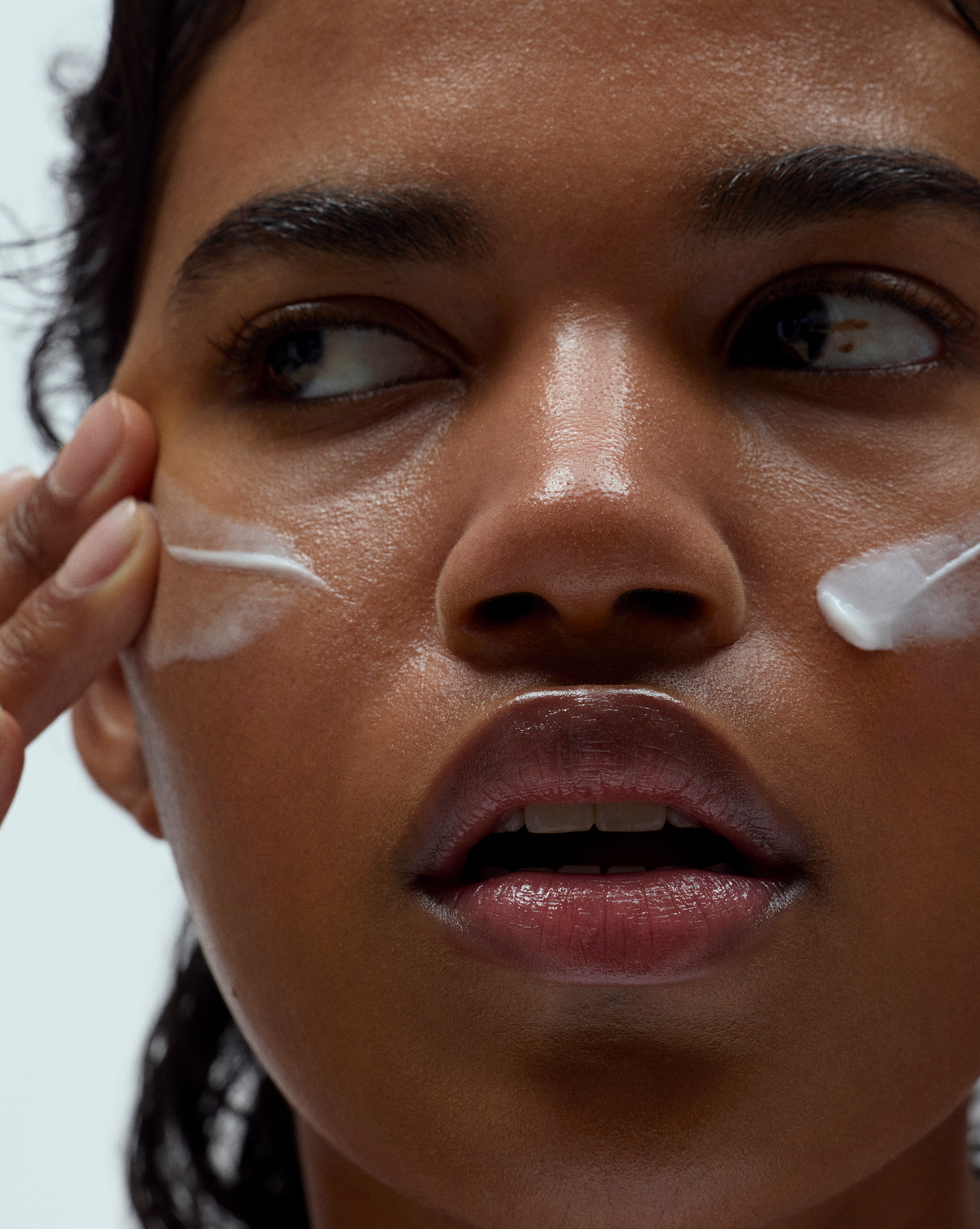 Person applying Skin Mercy Recovery Cream to their cheek