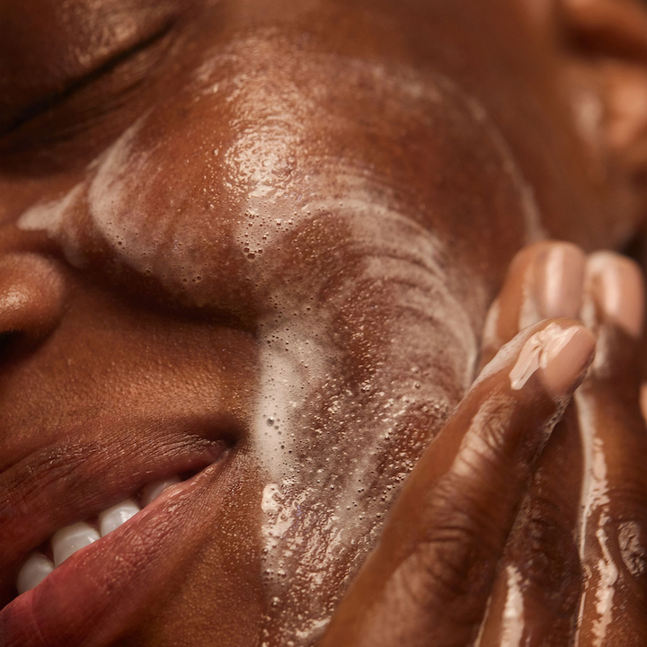 Person cleansing their face with Baptism foam